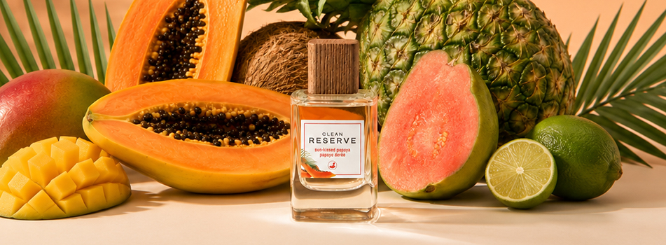Clean Reserve Sun-Kissed Papaya Parfumflasche umgeben von tropischen Früchten wie Papaya, Ananas, Guave und Mango