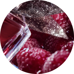 Nahaufnahme von glitzernden Parfümnoten und roten Himbeeren