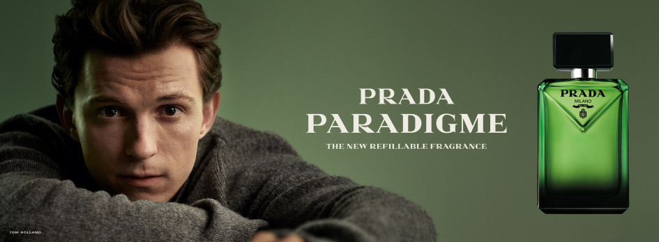 Werbebanner für den Duft Prada Paradigme: Eine Person blickt nach vorne, der Oberkörper lehnt leicht über eine Fläche. Rechts daneben steht ein großer grüner, eckiger Parfümflakon. Auf der linken Seite befindet sich der Schriftzug ‚Prada Paradigme – The New Refillable Fragrance‘ auf dunkelgrünem Hintergrund.